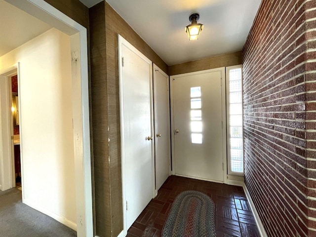 interior space featuring dark parquet flooring and brick wall