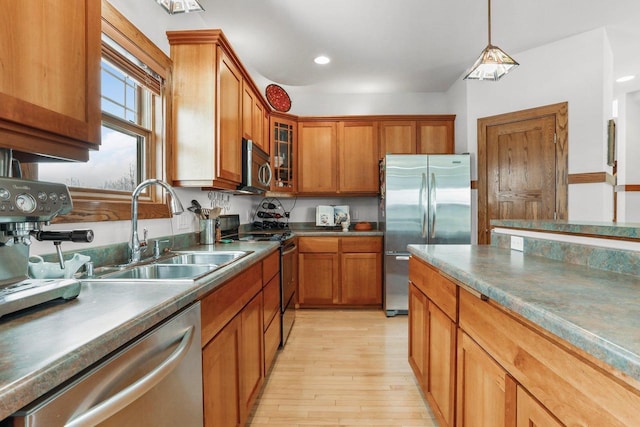 kitchen featuring stainless steel appliances, sink, pendant lighting, and light wood-type flooring