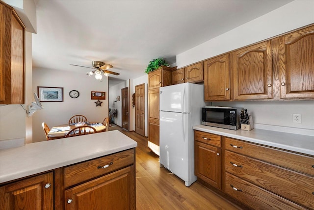 kitchen with light wood-type flooring, ceiling fan, and white refrigerator