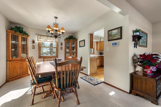 dining area with light carpet and a chandelier