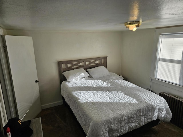 bedroom featuring radiator heating unit and a textured ceiling