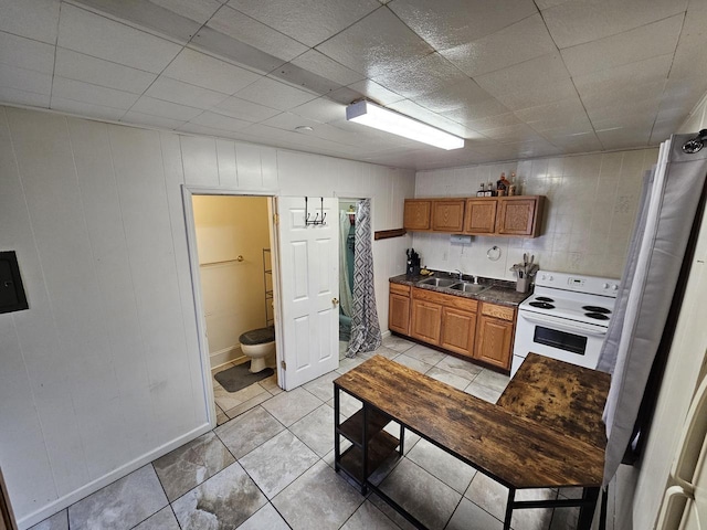 kitchen featuring electric stove, sink, and light tile patterned floors