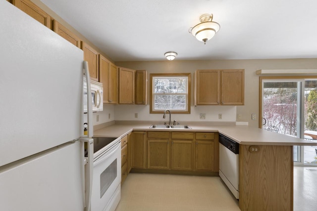 kitchen with white appliances, plenty of natural light, sink, and kitchen peninsula