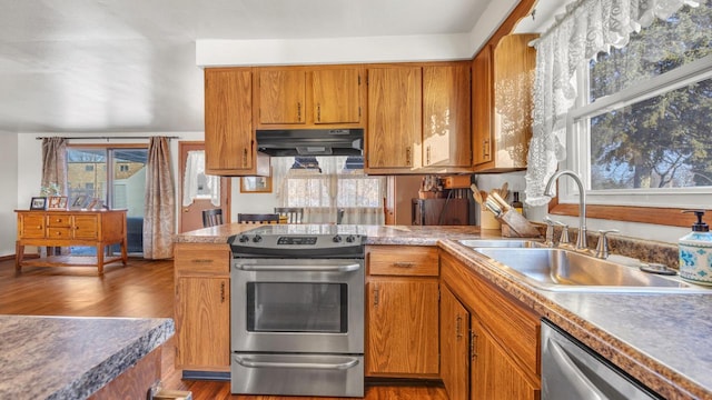 kitchen featuring stainless steel appliances, sink, dark hardwood / wood-style flooring, and extractor fan