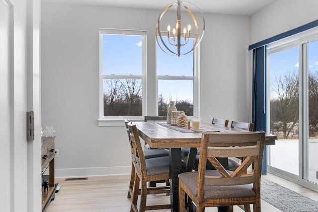 dining area with plenty of natural light, an inviting chandelier, and light hardwood / wood-style floors