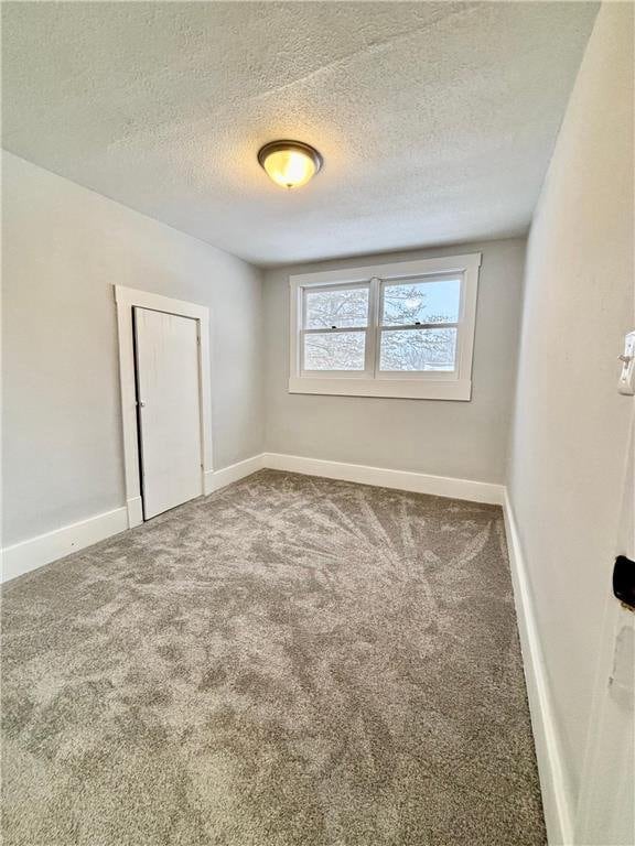 unfurnished room featuring carpet flooring and a textured ceiling