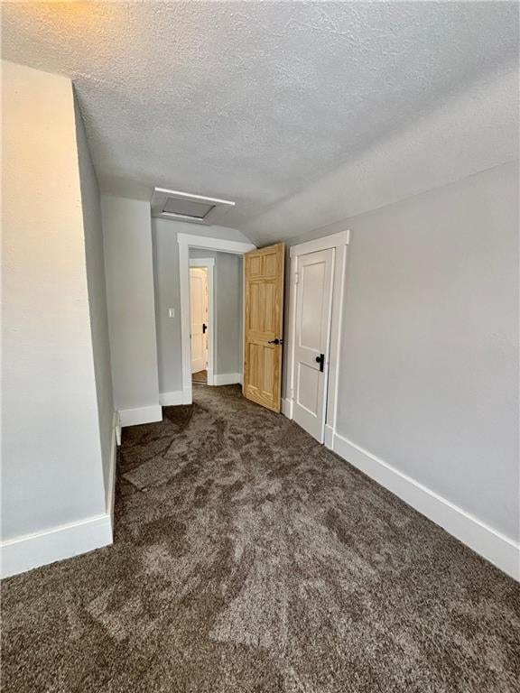 unfurnished bedroom with dark colored carpet and a textured ceiling