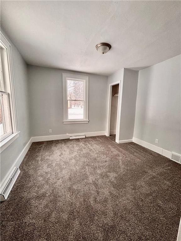 spare room featuring baseboard heating, carpet floors, and a textured ceiling