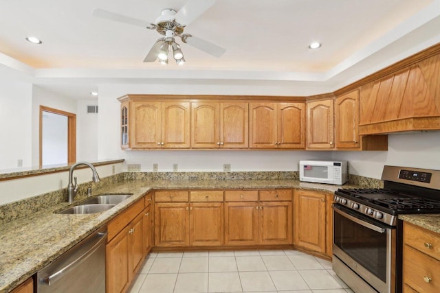 kitchen featuring sink, light stone counters, light tile patterned floors, appliances with stainless steel finishes, and ceiling fan