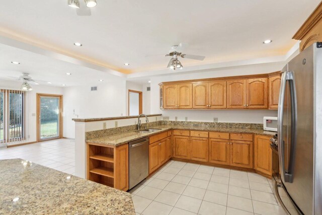 kitchen featuring sink, stainless steel appliances, light stone counters, light tile patterned flooring, and kitchen peninsula