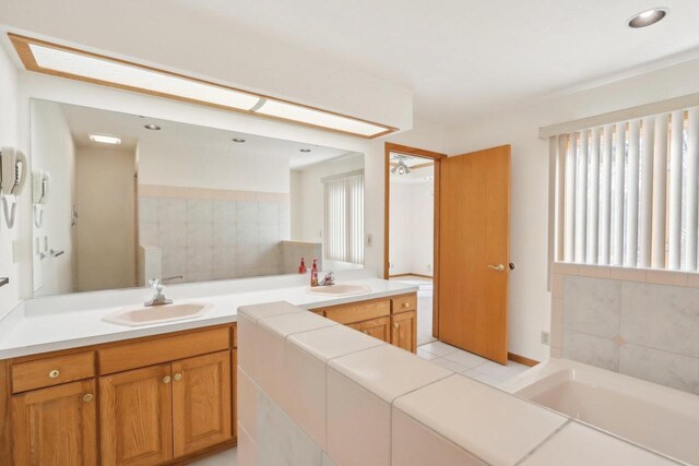 bathroom with a bathing tub, vanity, and tile patterned floors