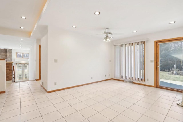 unfurnished room featuring ceiling fan, a healthy amount of sunlight, a fireplace, and light tile patterned floors