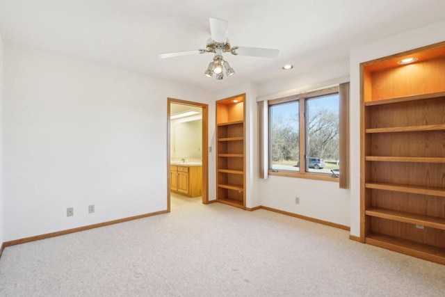 unfurnished bedroom with ceiling fan, ensuite bath, sink, and light carpet