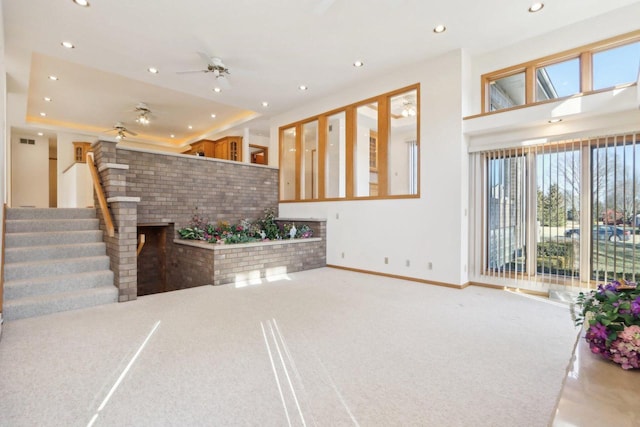 unfurnished living room with ceiling fan and a tray ceiling