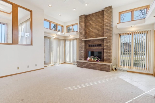 unfurnished living room featuring light tile patterned floors, a brick fireplace, and a high ceiling