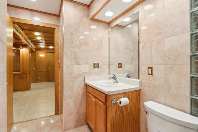 bathroom featuring tile walls, vanity, toilet, crown molding, and tile patterned floors