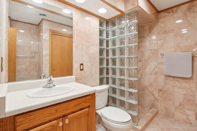 bathroom featuring vanity, toilet, tile walls, and a tile shower