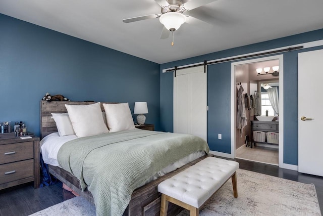 bedroom featuring ceiling fan, a barn door, and dark wood-type flooring