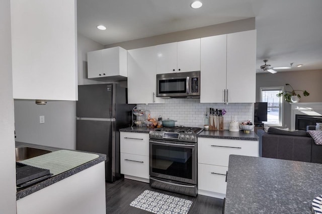 kitchen with white cabinetry, dark hardwood / wood-style flooring, ceiling fan, appliances with stainless steel finishes, and decorative backsplash