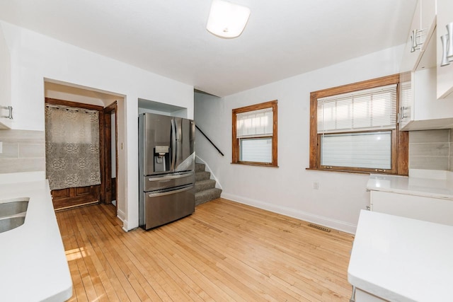 kitchen with white cabinetry, stainless steel fridge, sink, and light wood-type flooring