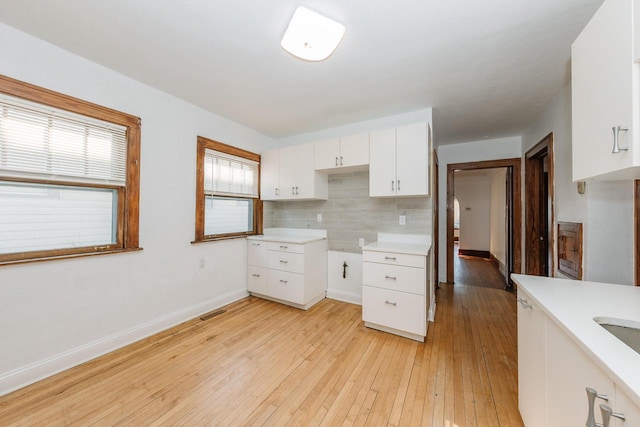 kitchen with tasteful backsplash, light hardwood / wood-style flooring, and white cabinets