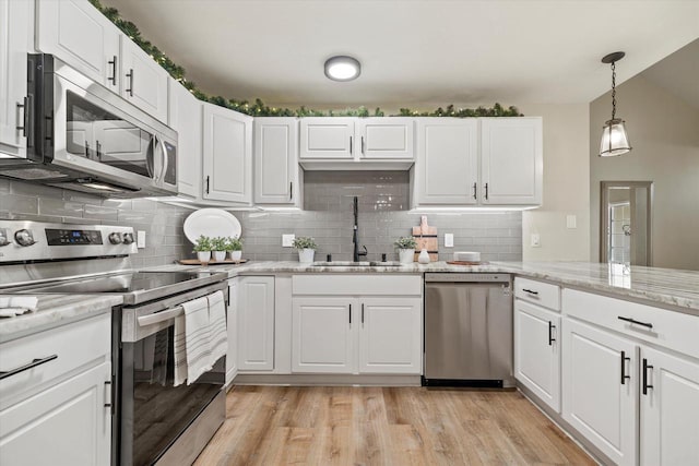 kitchen featuring sink, light wood-type flooring, appliances with stainless steel finishes, light stone countertops, and white cabinets