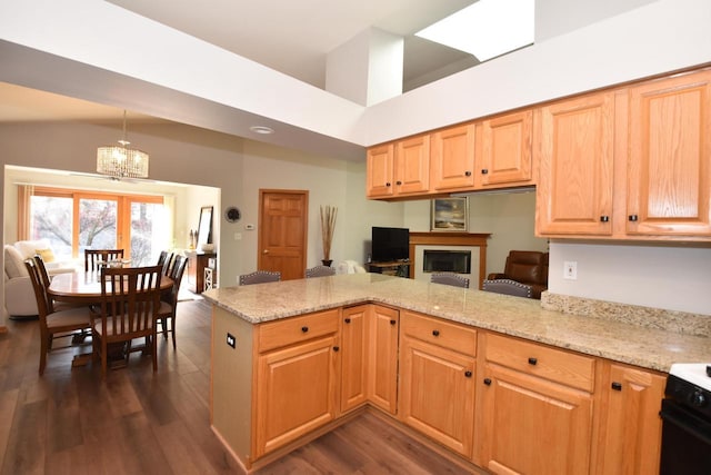 kitchen featuring light stone countertops, dark hardwood / wood-style floors, black range, and kitchen peninsula