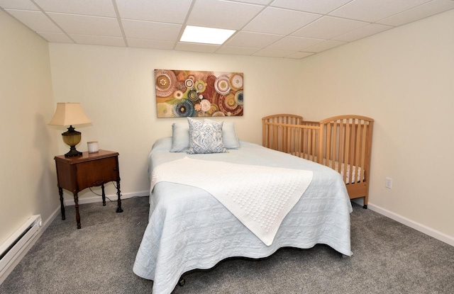 carpeted bedroom featuring a baseboard heating unit and a drop ceiling