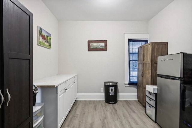 interior space with white cabinets, stainless steel fridge, and light hardwood / wood-style floors