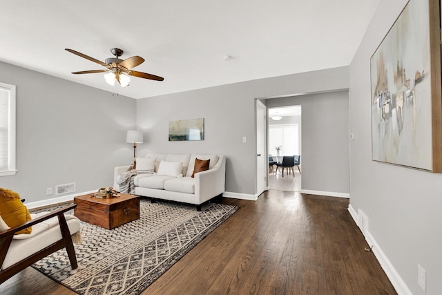 living room featuring dark wood-type flooring and ceiling fan