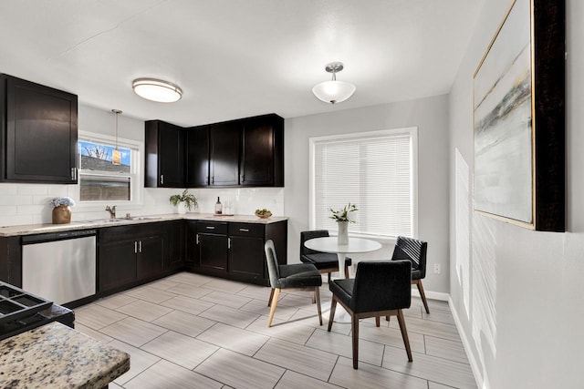 kitchen featuring sink, dishwasher, hanging light fixtures, tasteful backsplash, and light stone counters