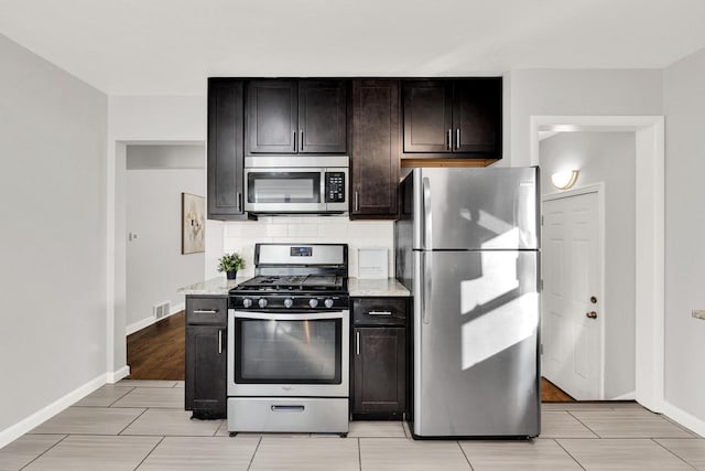 kitchen featuring tasteful backsplash, stainless steel appliances, light stone countertops, and dark brown cabinets