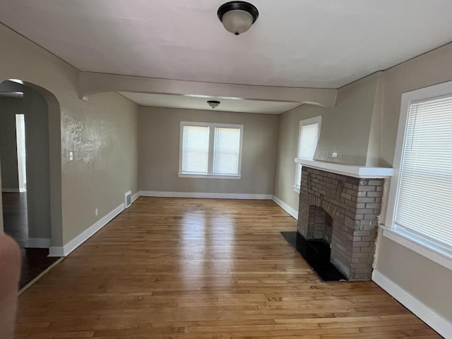 unfurnished living room with a brick fireplace and light hardwood / wood-style floors