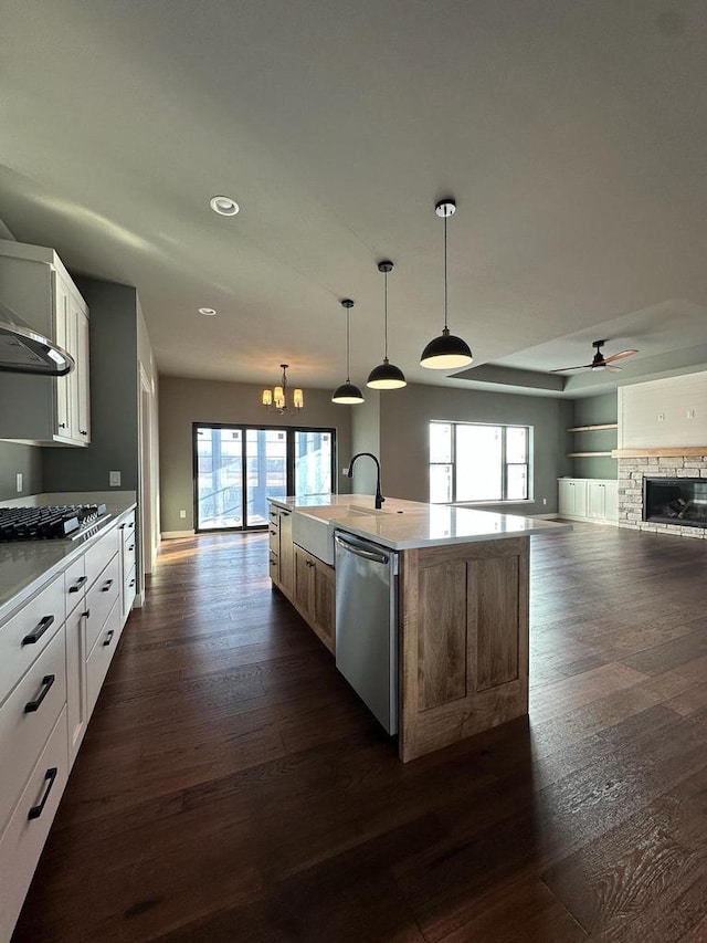 kitchen featuring white cabinetry, decorative light fixtures, a center island with sink, dark hardwood / wood-style flooring, and stainless steel appliances