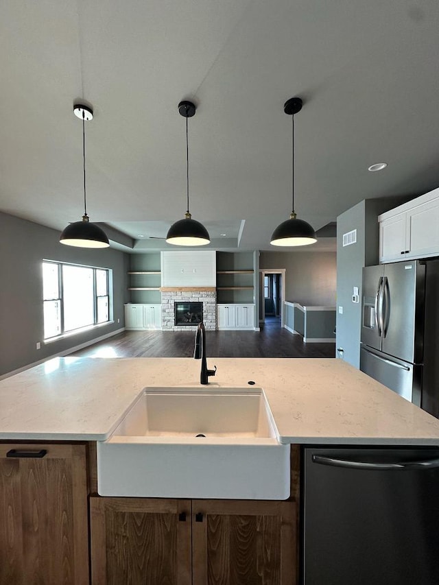 kitchen featuring stainless steel appliances, hanging light fixtures, sink, and a center island with sink