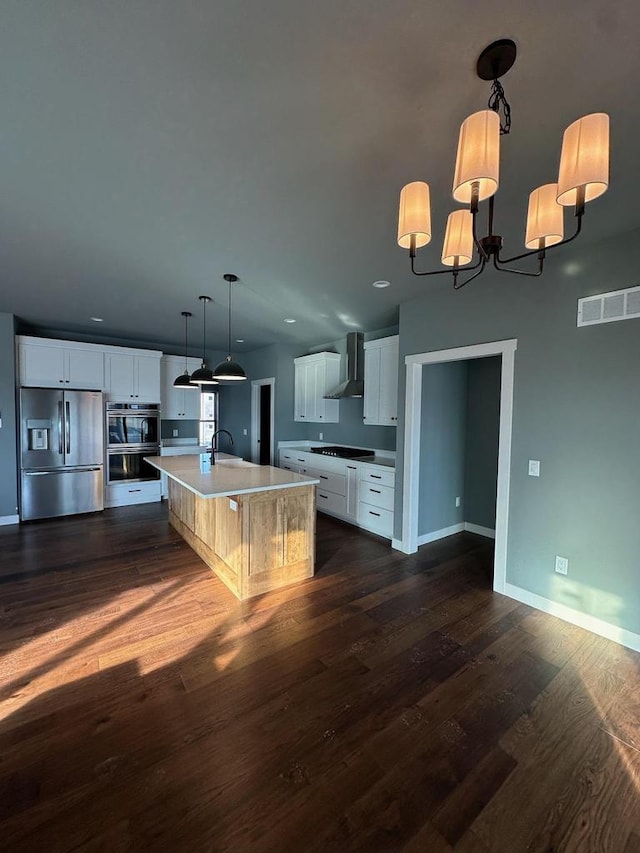 kitchen with white cabinetry, wall chimney range hood, a large island with sink, and stainless steel refrigerator with ice dispenser