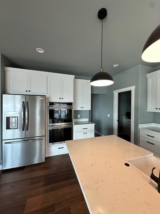 kitchen featuring light stone countertops, stainless steel appliances, and white cabinets