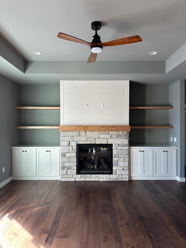 unfurnished living room with ceiling fan, dark wood-type flooring, built in features, and a fireplace