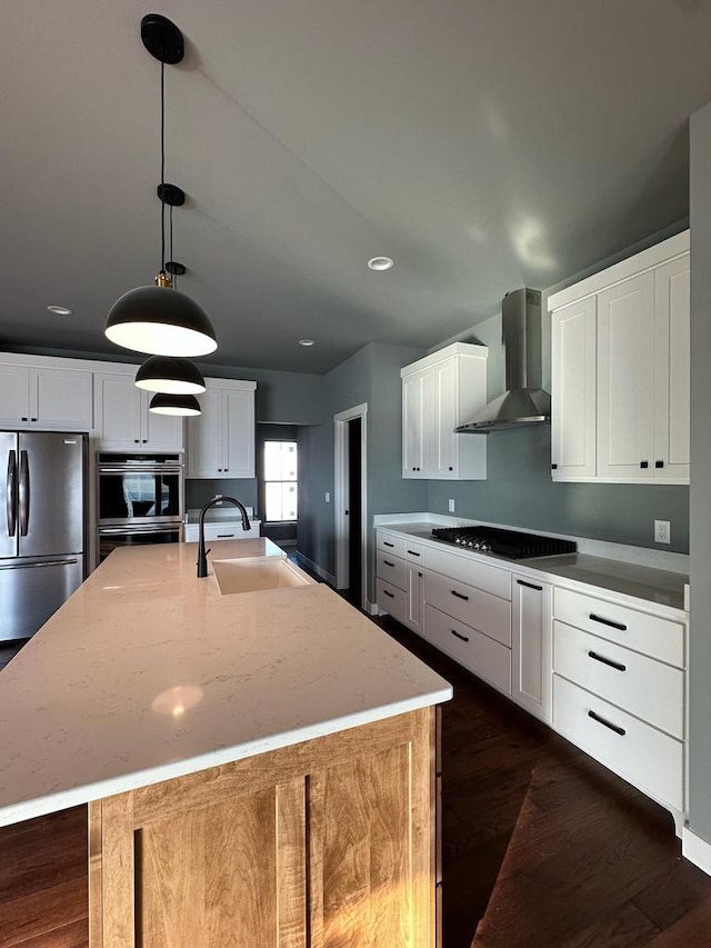 kitchen featuring an island with sink, appliances with stainless steel finishes, and wall chimney range hood