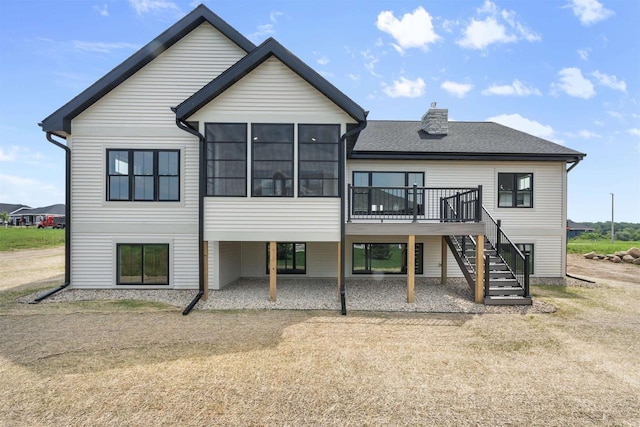 rear view of property featuring a sunroom, a yard, and a deck