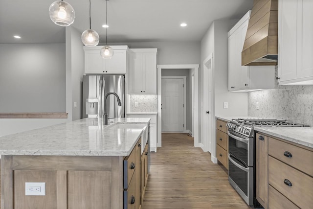 kitchen with stainless steel appliances, an island with sink, and white cabinets