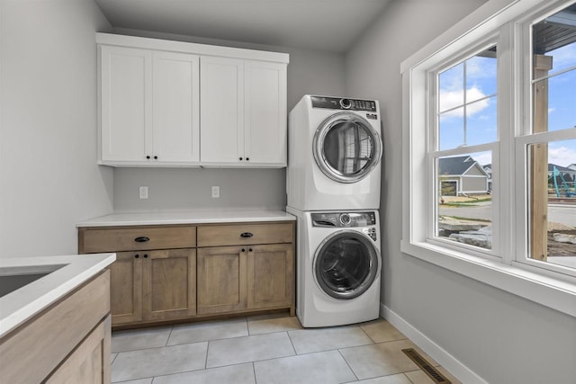 822 Westbridge Trl, Waunakee, WI 53597 - laundry area featuring cabinets, stacked washing maching and dryer, and light tile patterned floors