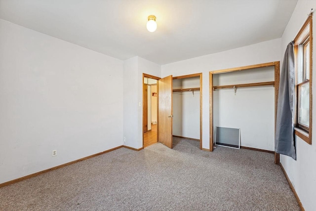 unfurnished bedroom featuring carpet and two closets