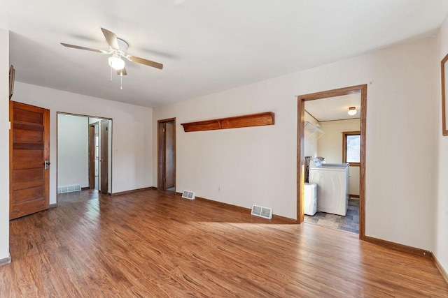 spare room with hardwood / wood-style floors, washer / dryer, and ceiling fan