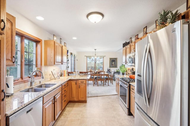 kitchen featuring appliances with stainless steel finishes, decorative light fixtures, sink, kitchen peninsula, and a healthy amount of sunlight