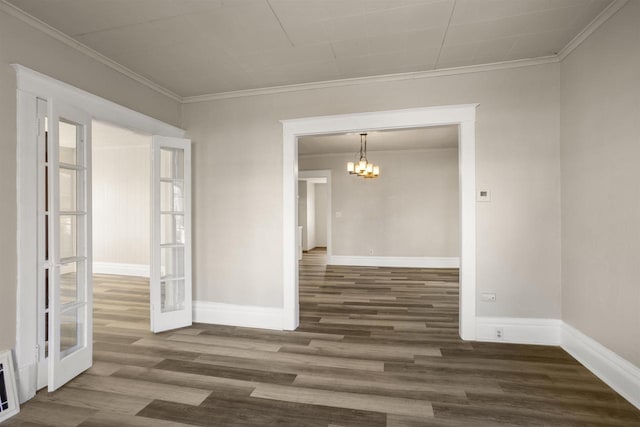 spare room with crown molding, dark hardwood / wood-style floors, an inviting chandelier, and french doors