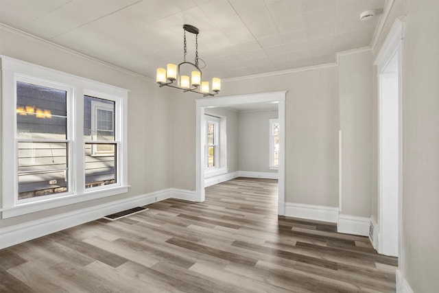 unfurnished dining area featuring an inviting chandelier, hardwood / wood-style floors, and crown molding