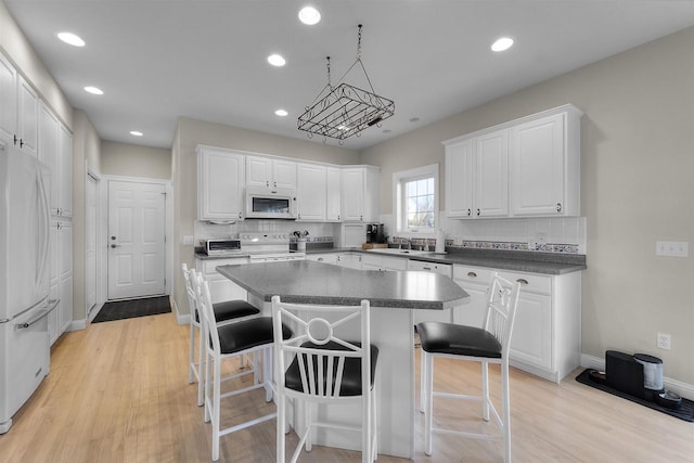 1809 Shady Point Dr, Verona, WI 53593 - kitchen featuring white appliances, white cabinetry, a center island, a kitchen bar, and decorative backsplash
