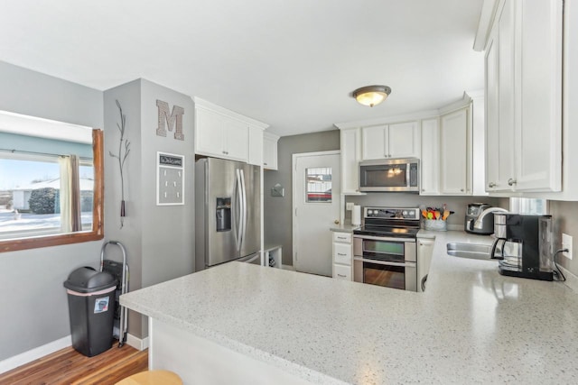 kitchen featuring white cabinetry, kitchen peninsula, and appliances with stainless steel finishes