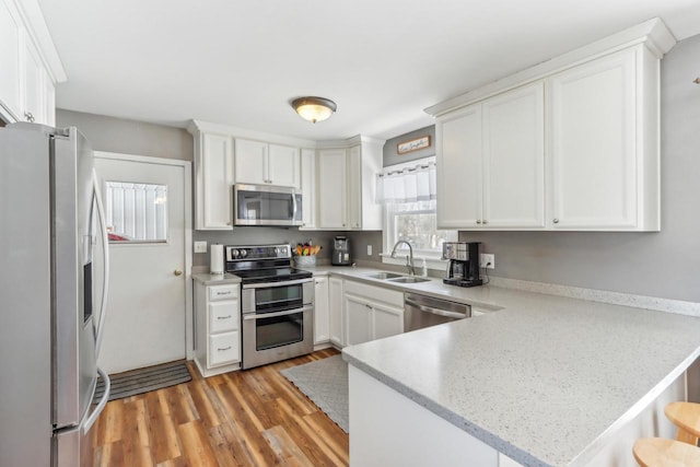 kitchen featuring white cabinetry, appliances with stainless steel finishes, sink, and kitchen peninsula